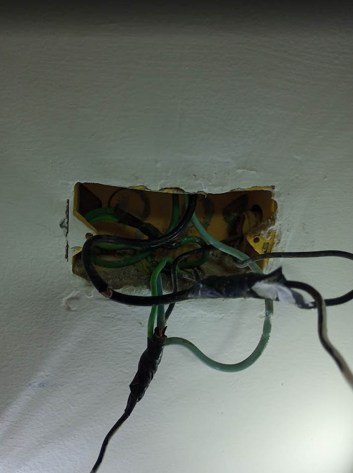 Tomada e fiação antigas encontradas em obra, com instalação inviável para a carga atual