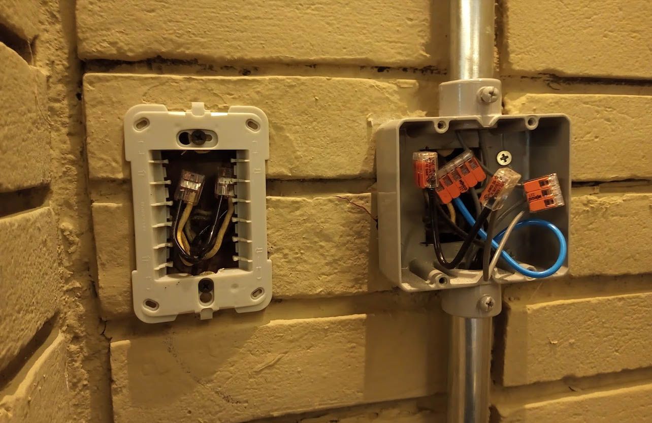 A mesma parede de tijolos depois do serviço, com infraestrutura aparente em condulete e emendas feitas com conectores de alavanca